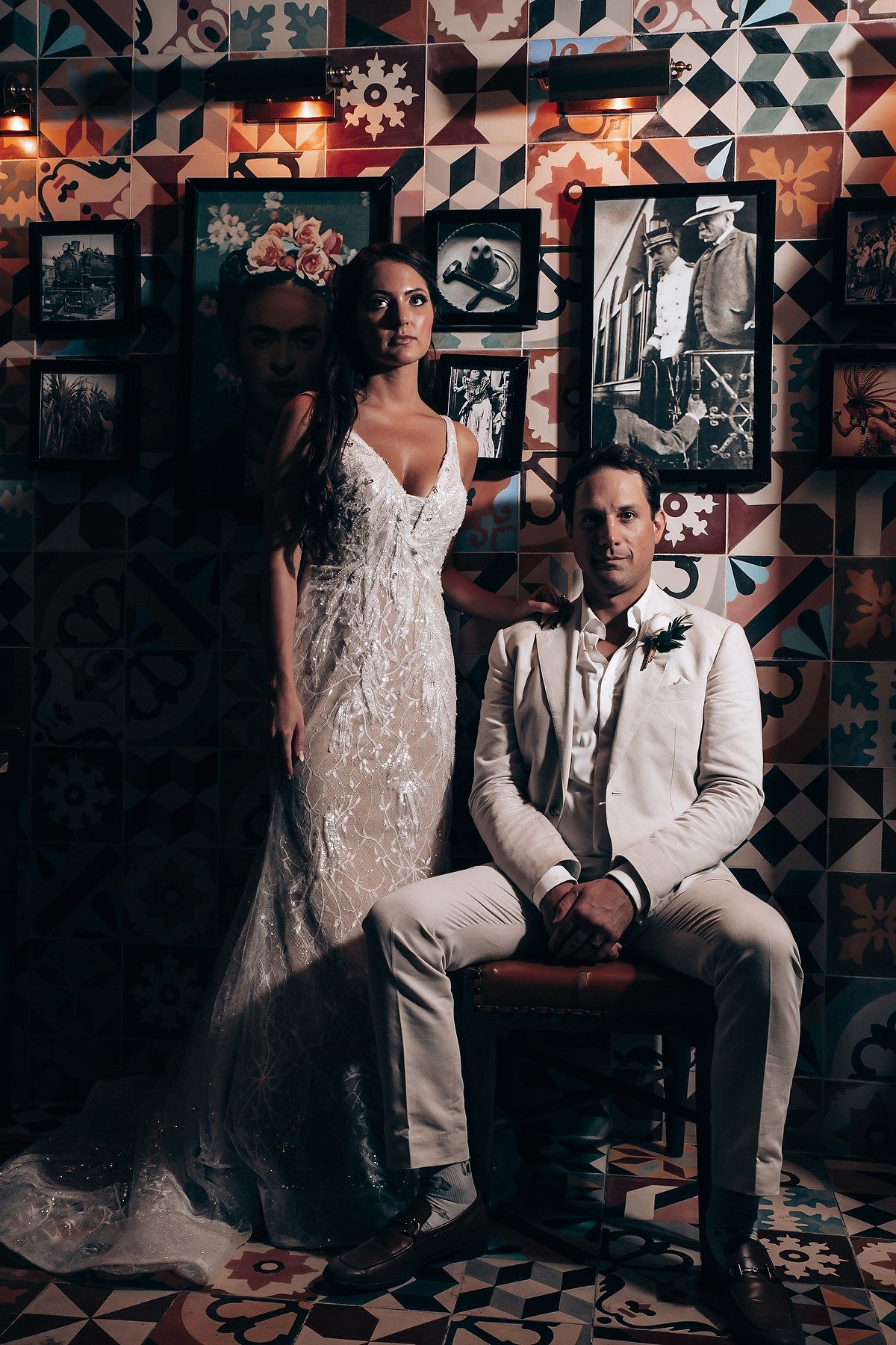 A wedding photoshoot in front of a geometric patterned wall with moody lighting.