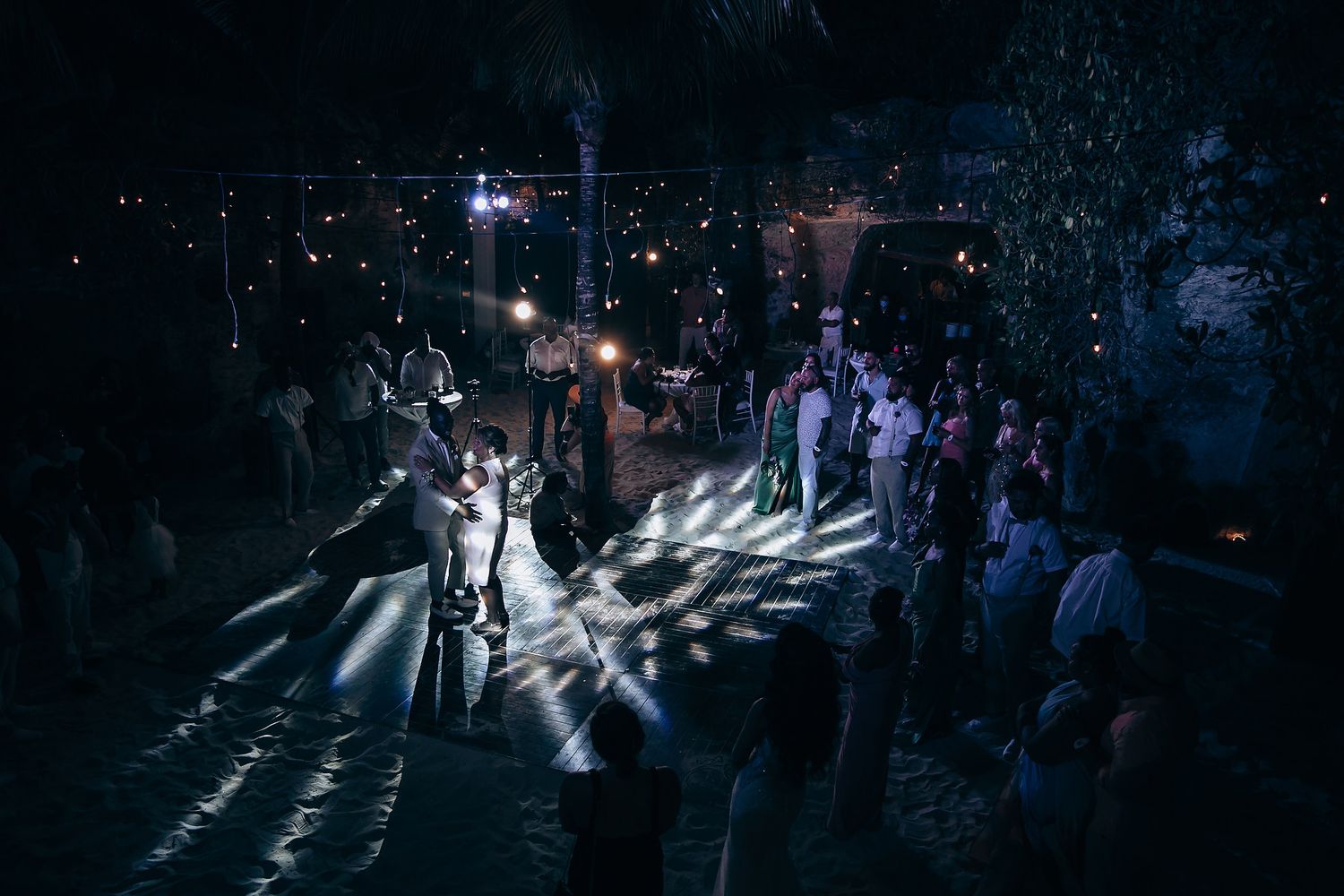 Dramatic nighttime wedding reception with spotlights creating patterns on dance floor.