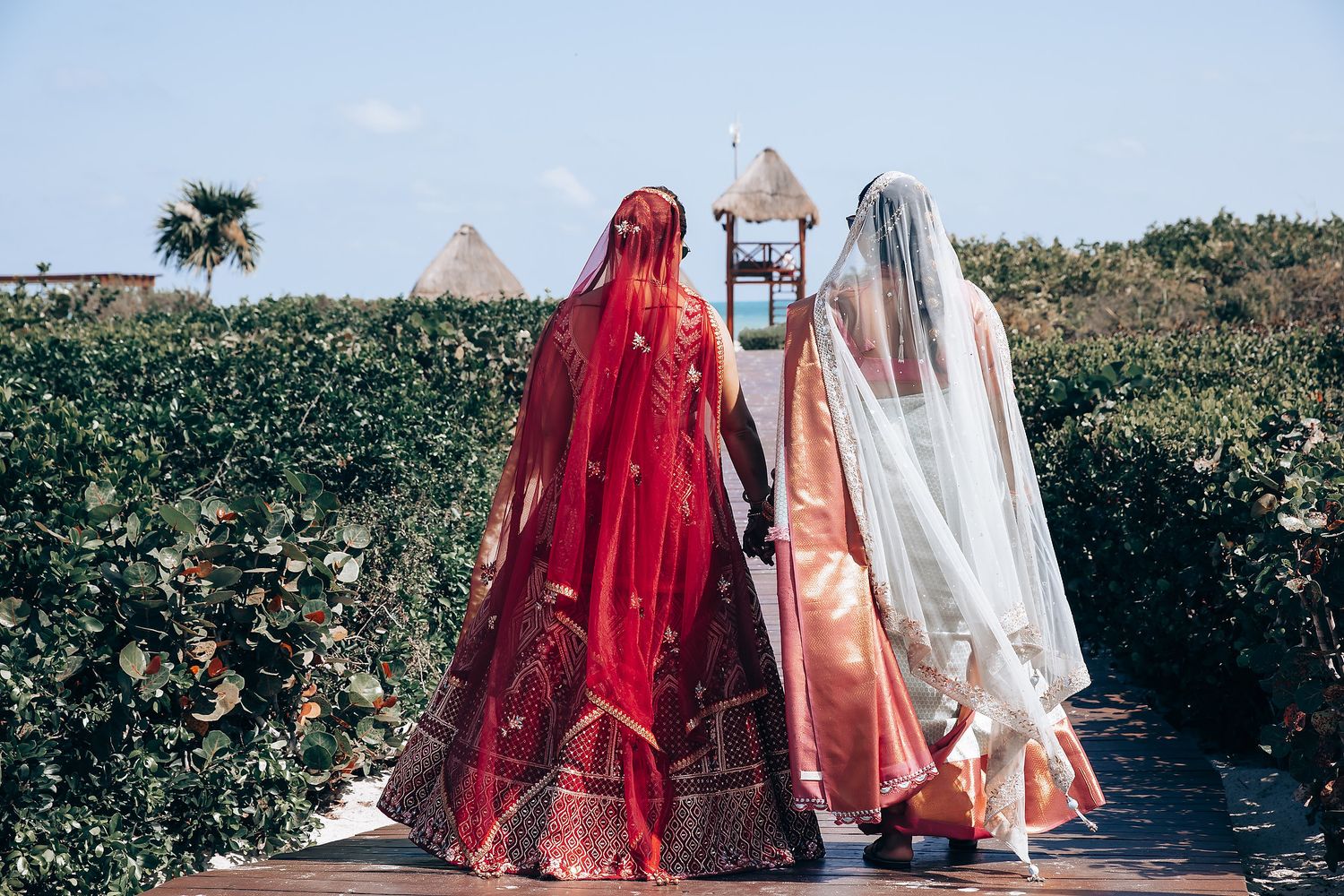 Wedding guests in colorful traditional attire celebrate on a beach during a destination ceremony.