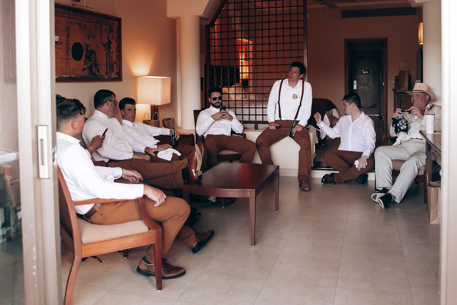 Wedding party relaxing and socializing in a rustic indoor venue with warm lighting.