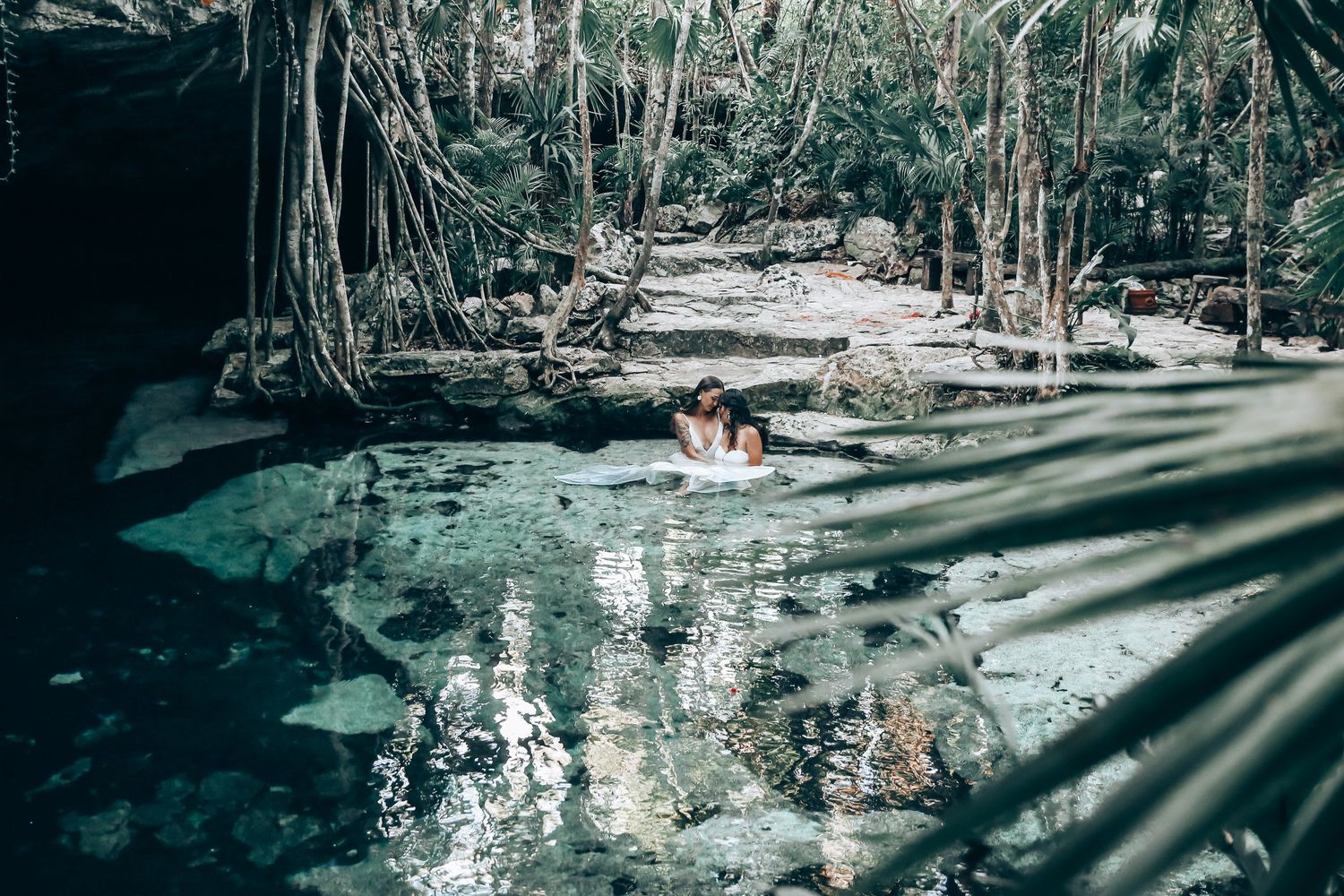 Swimmers enjoy the crystal clear waters of a natural cenote pool surrounded by jungle.