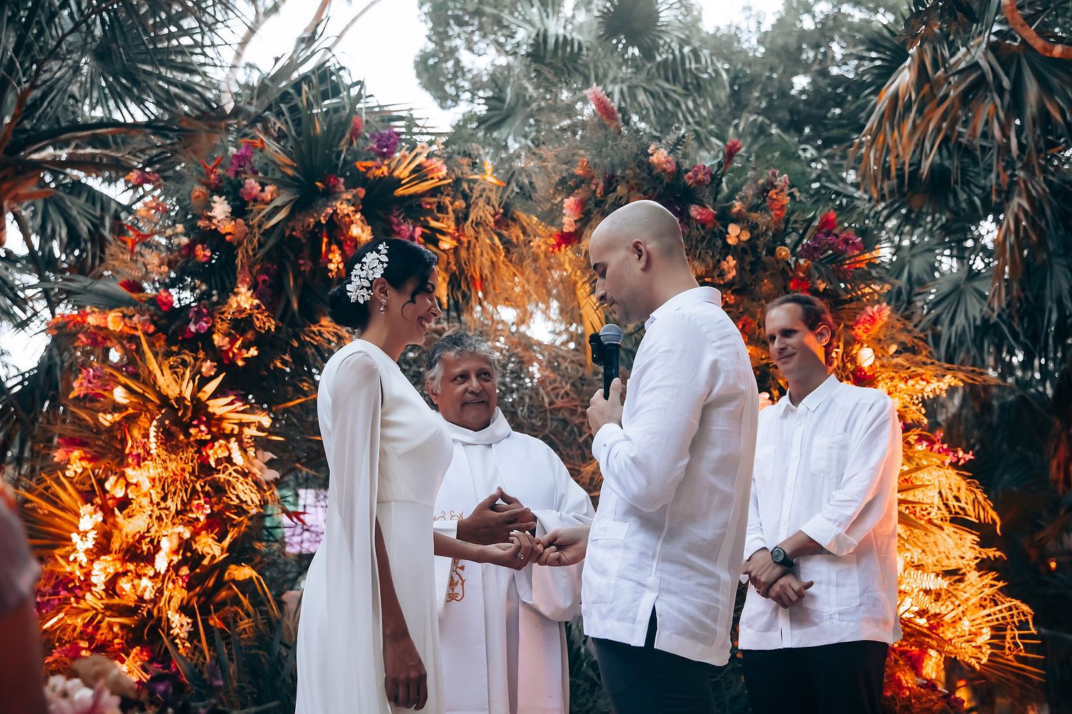 Wedding reception setup in a lush garden setting with warm lighting and tropical decor.