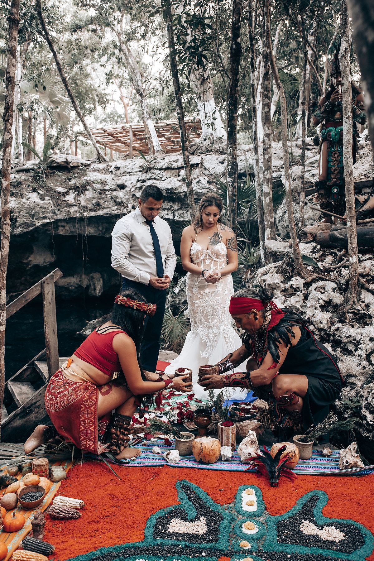Traditional indigenous ceremony being performed on vibrant red earth surrounded by eucalyptus trees.