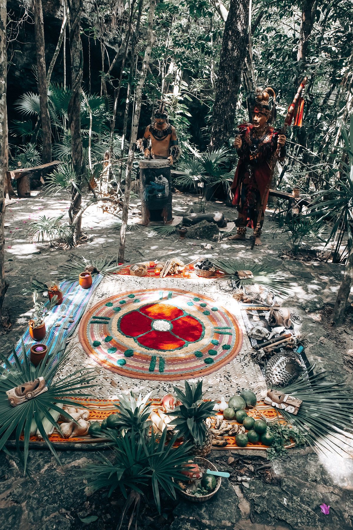 Traditional Mayan spiritual ceremony with colorful sand mandalas and ritual objects arranged in a forest setting.