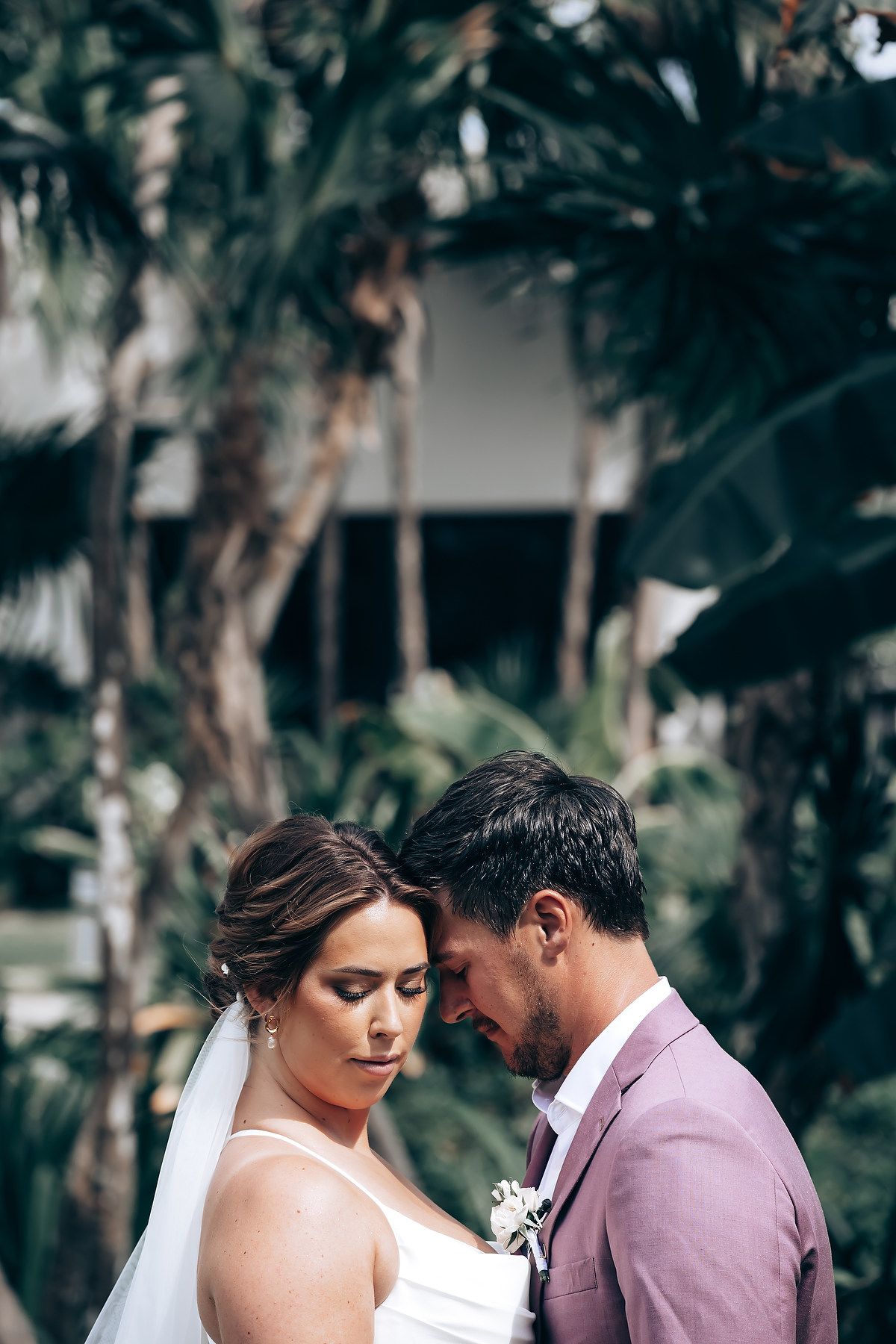 A romantic moment between a couple in a tropical garden setting with lush greenery.