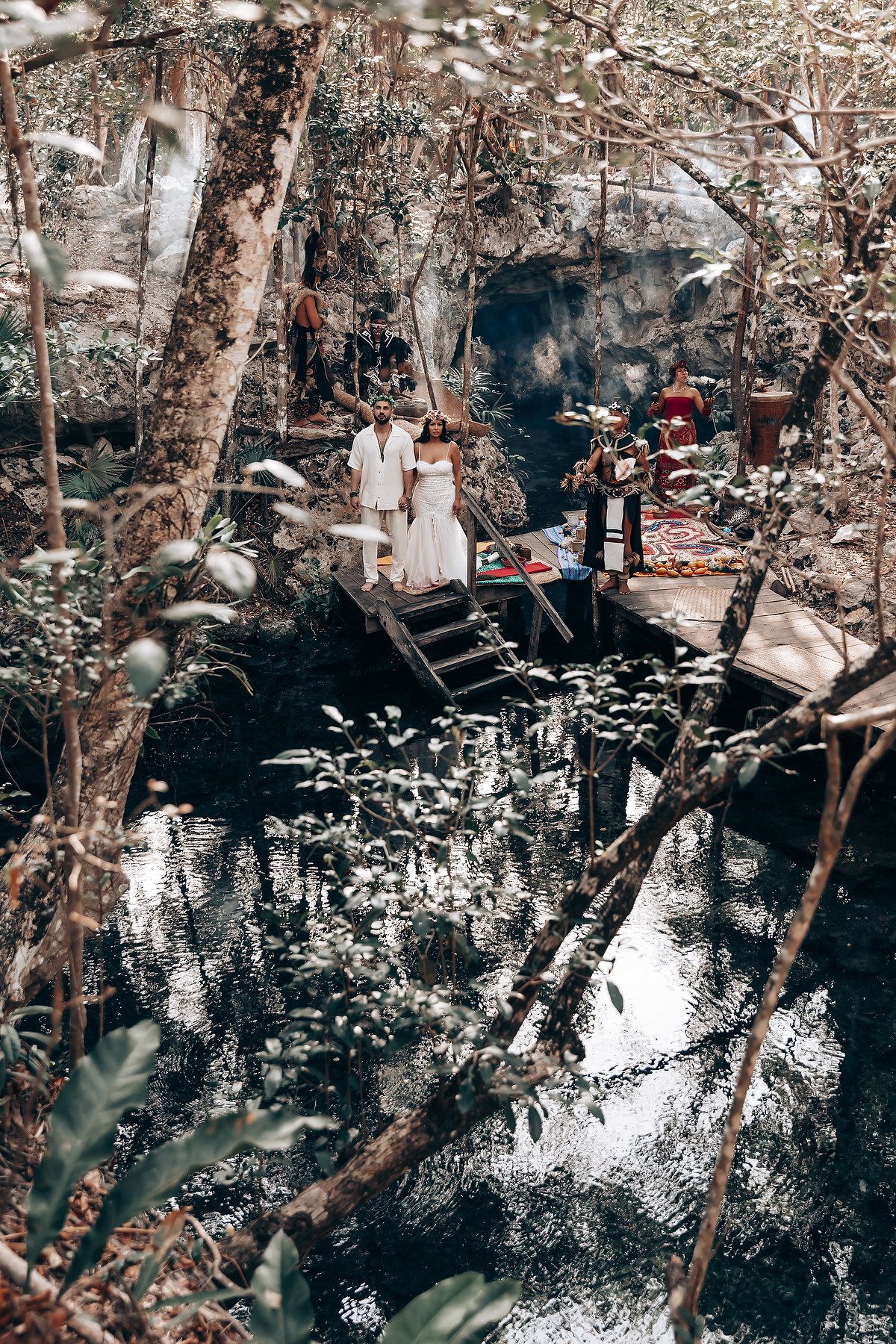 Tranquil cenote reflection in dark waters surrounded by rocky formations and lush vegetation.