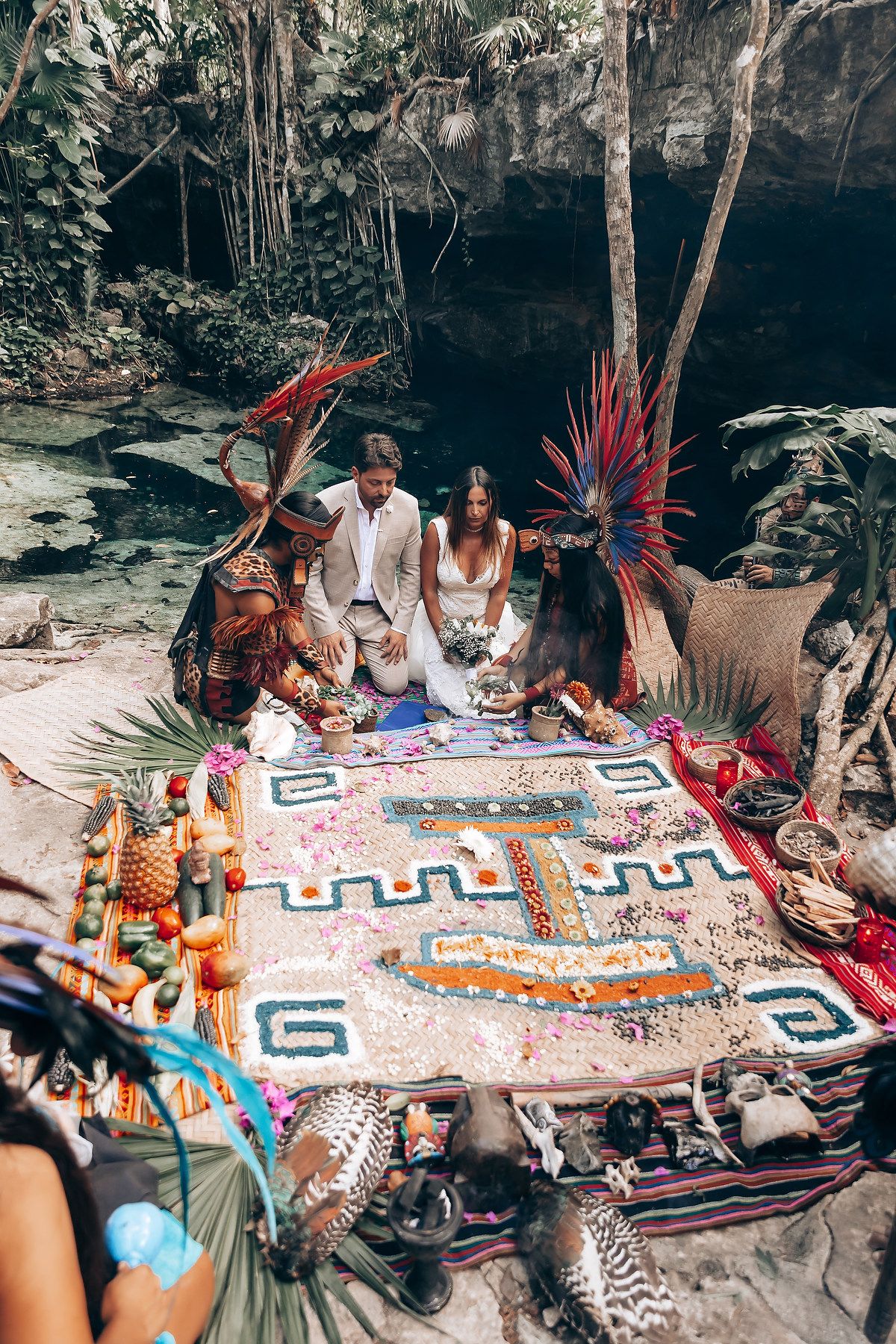 Colorful traditional Mayan blanket displayed on ground during spiritual ceremony in jungle setting.