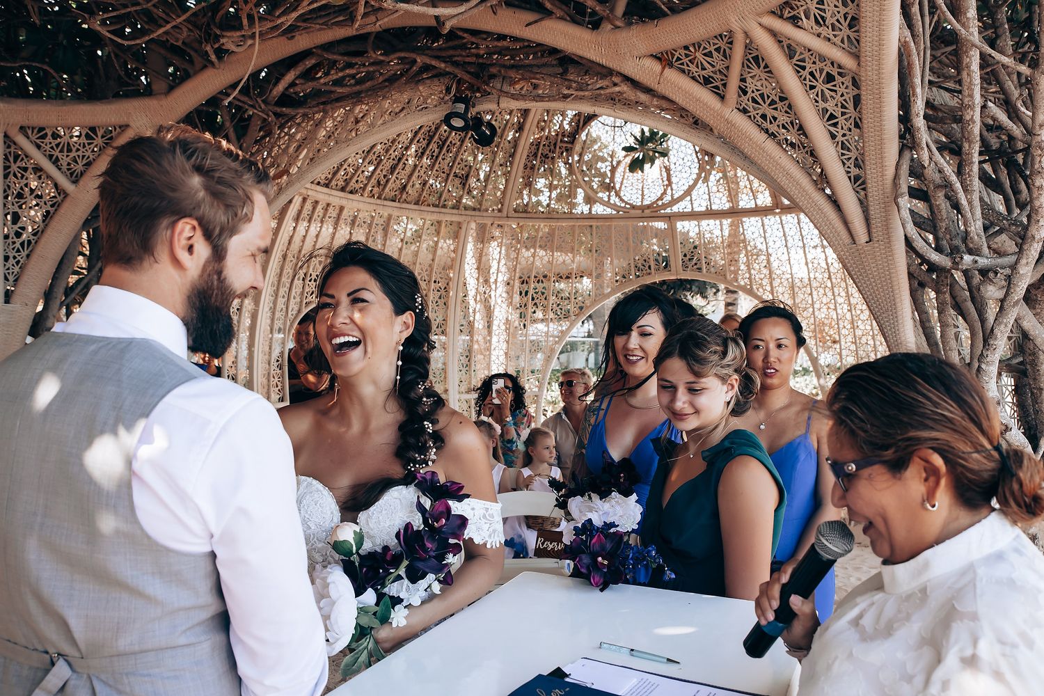 Wedding celebration under rustic wooden pergola with natural decor.