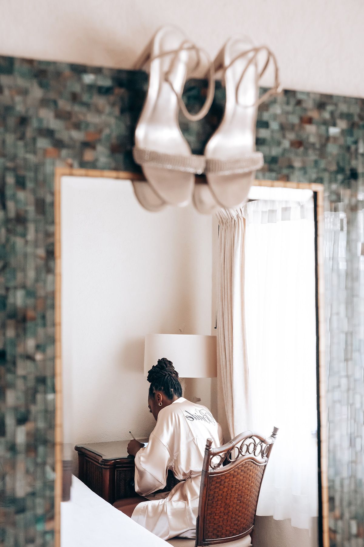 Wedding dress displayed in a room with brick walls and rattan furniture.
