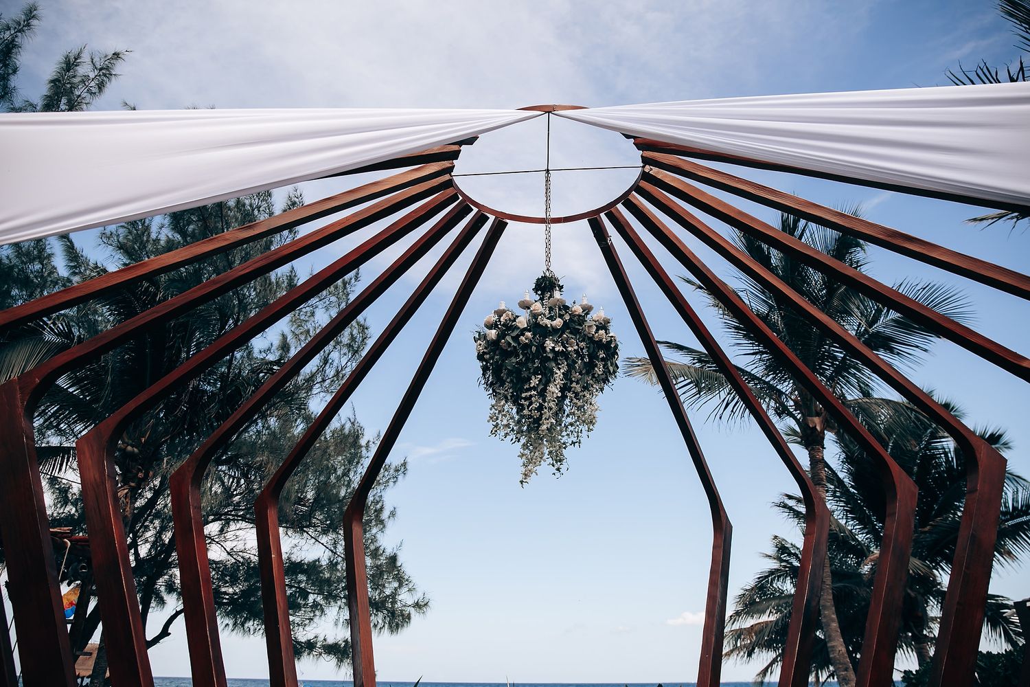 White canopy tent structure with wooden beams against a blue sky.