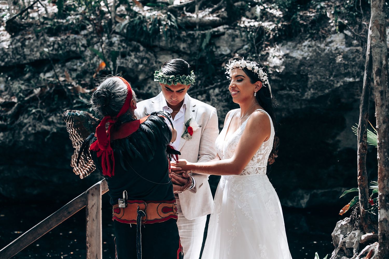 Outdoor wedding ceremony with participants standing among trees and natural rock formations.