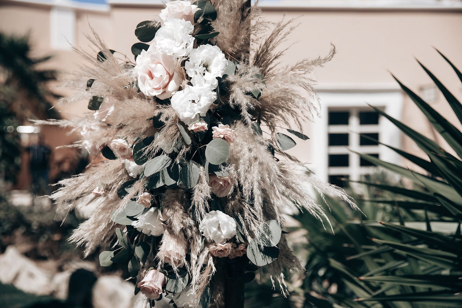 A bouquet of white flowers with feathers and other natural elements.