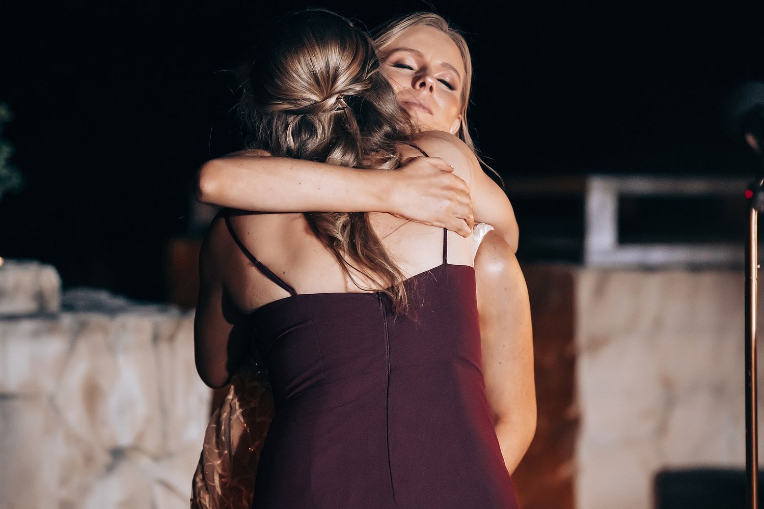 Two women embracing in a warm hug at night.