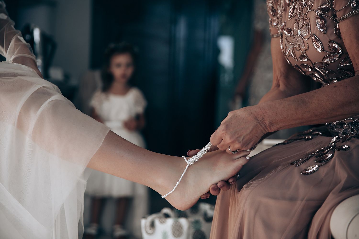 Hands helping with wedding dress details and final preparations before the ceremony.