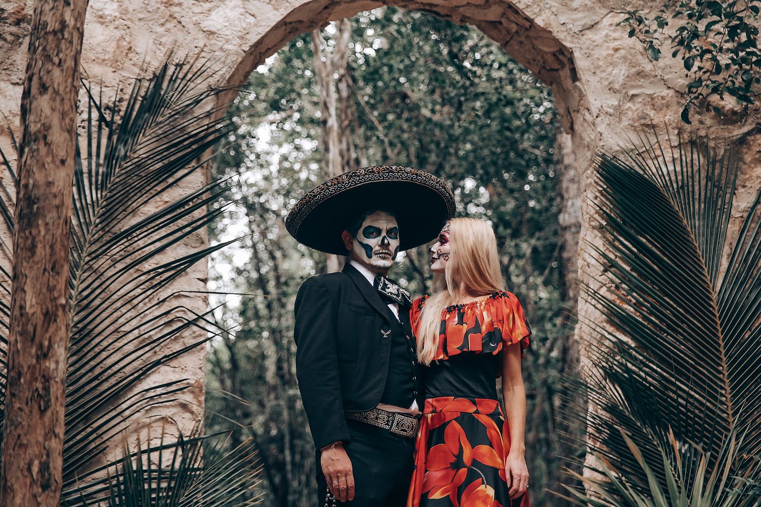 Forest photoshoot featuring traditional Dia de los Muertos costumes and stone architecture.