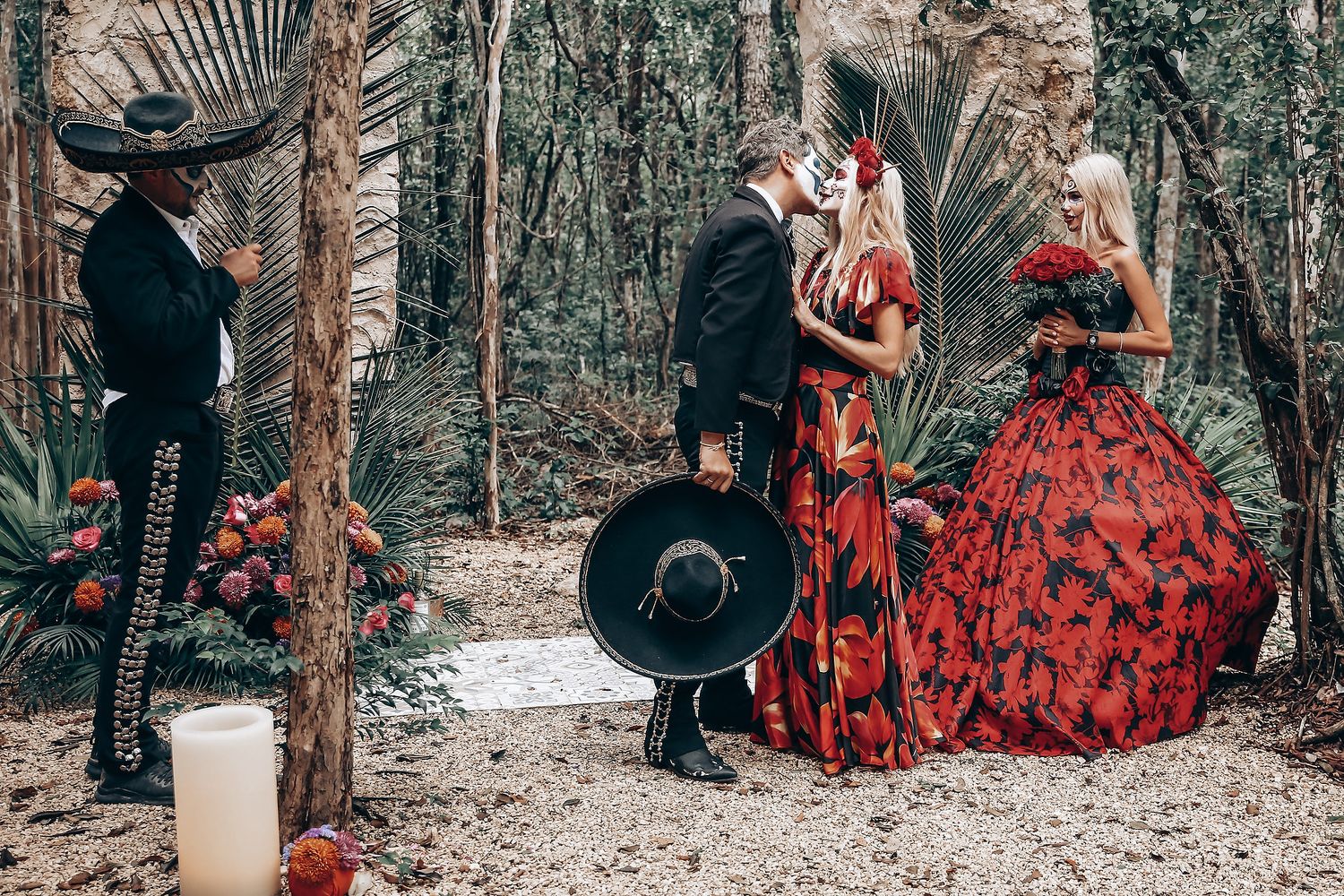 Wedding photo shoot with bride in flowing red dress and groom in traditional Mexican death motif costume.