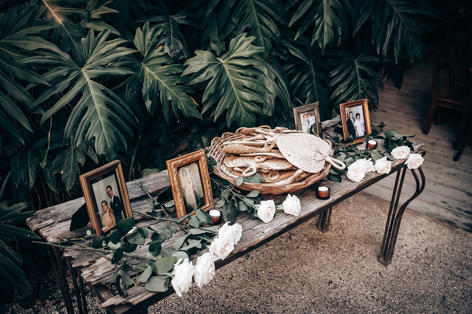 Tropical leaf decorations and wedding reception details arranged on a rustic surface.