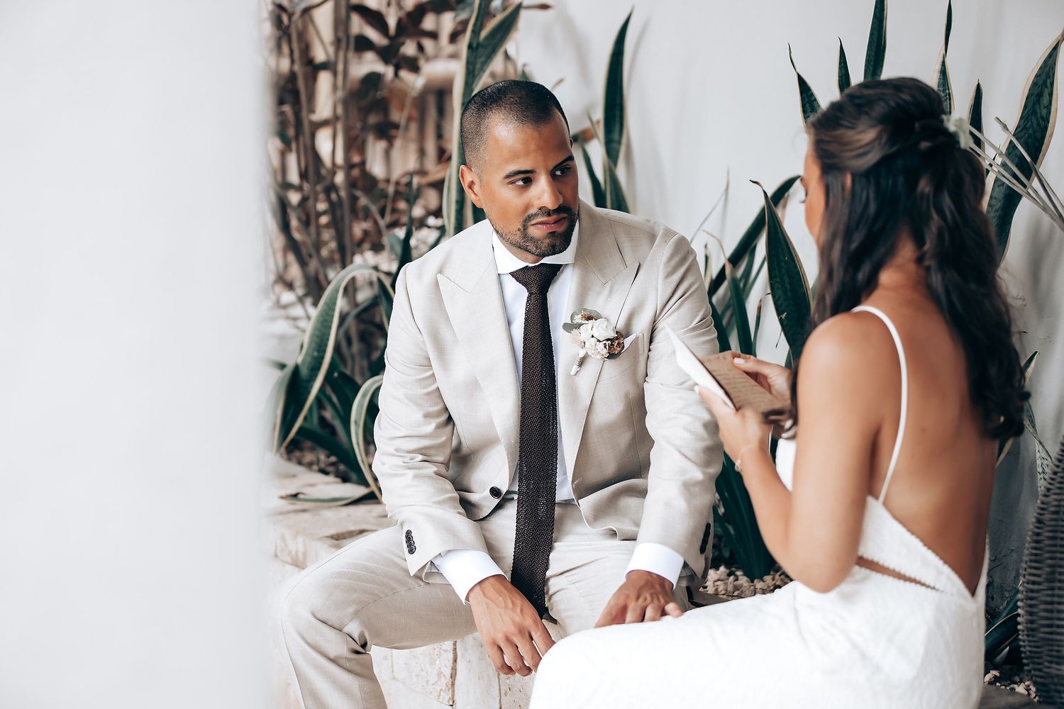 Intimate wedding moment captured between couple surrounded by lush tropical greenery.
