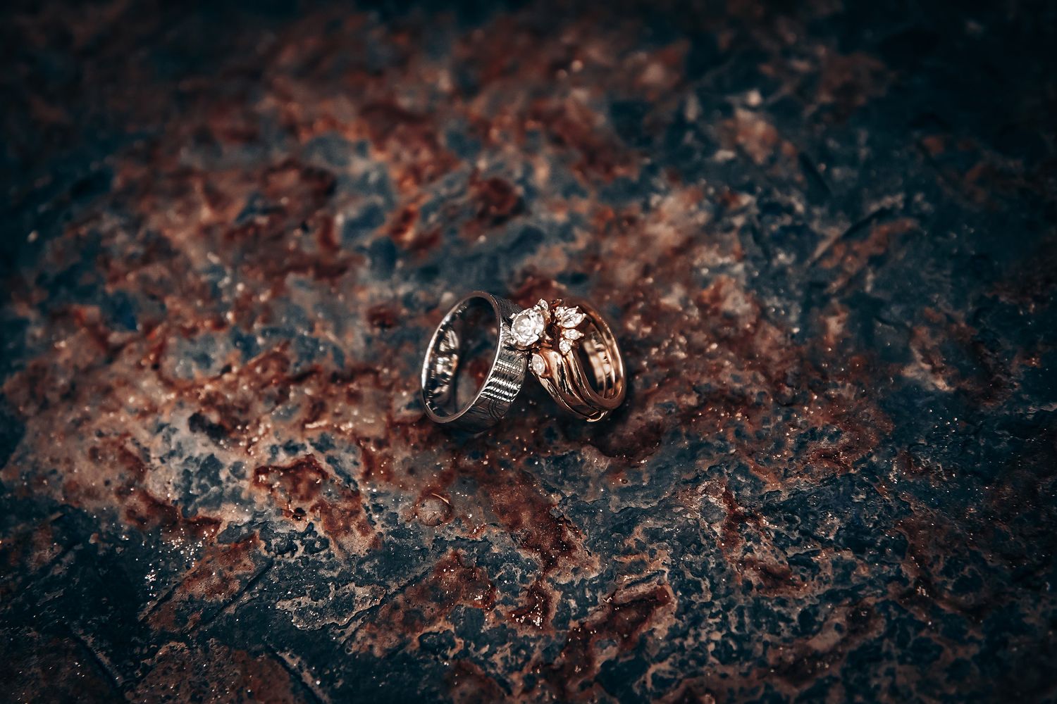 Dark textured surface with rusty orange and black patterns creating an abstract weathered appearance.