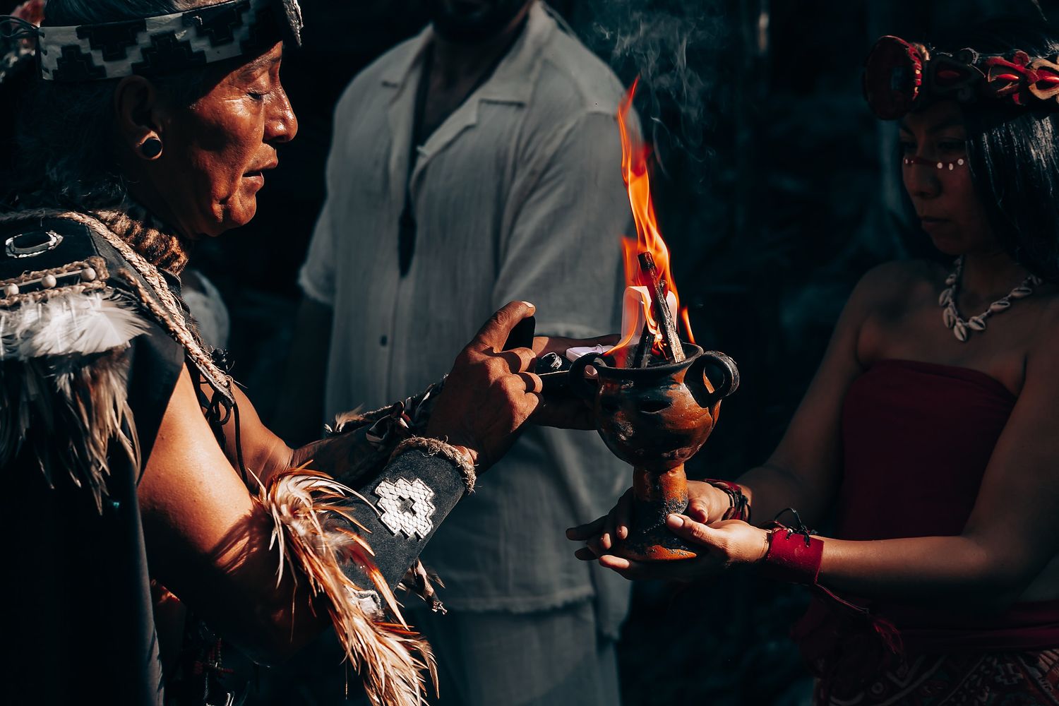 Traditional ceremony participants share sacred objects in a mystical forest setting.