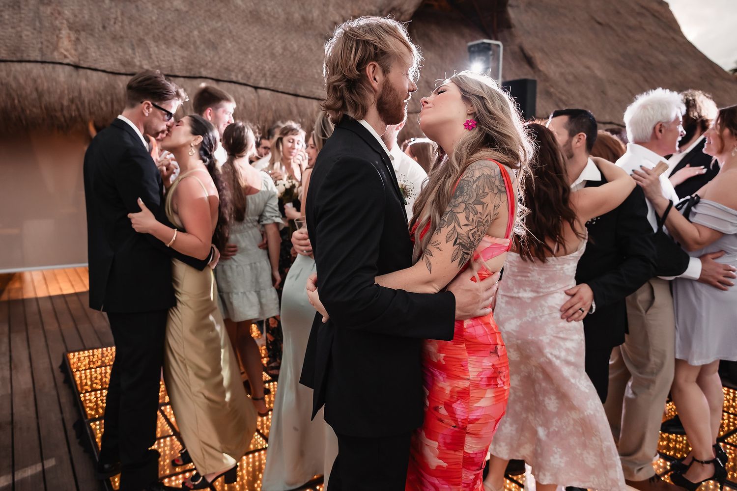 Couple dancing closely at a wedding reception with guests in formal attire on a decorated dance floor.