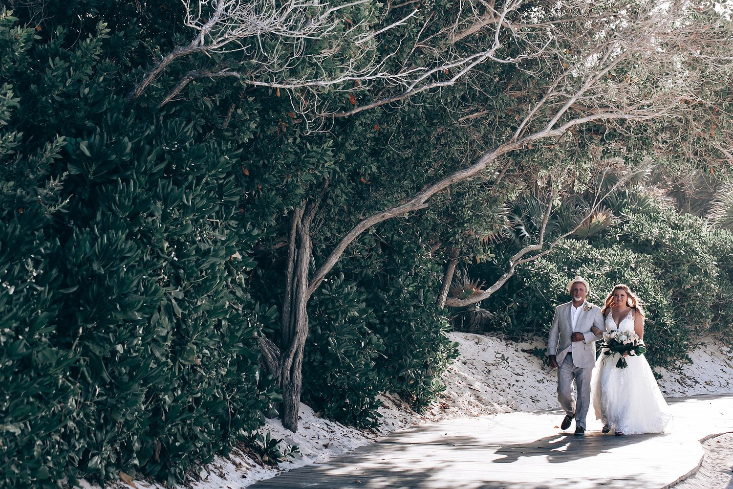 Snow-covered pathway surrounded by trees creates a winter wonderland wedding setting.