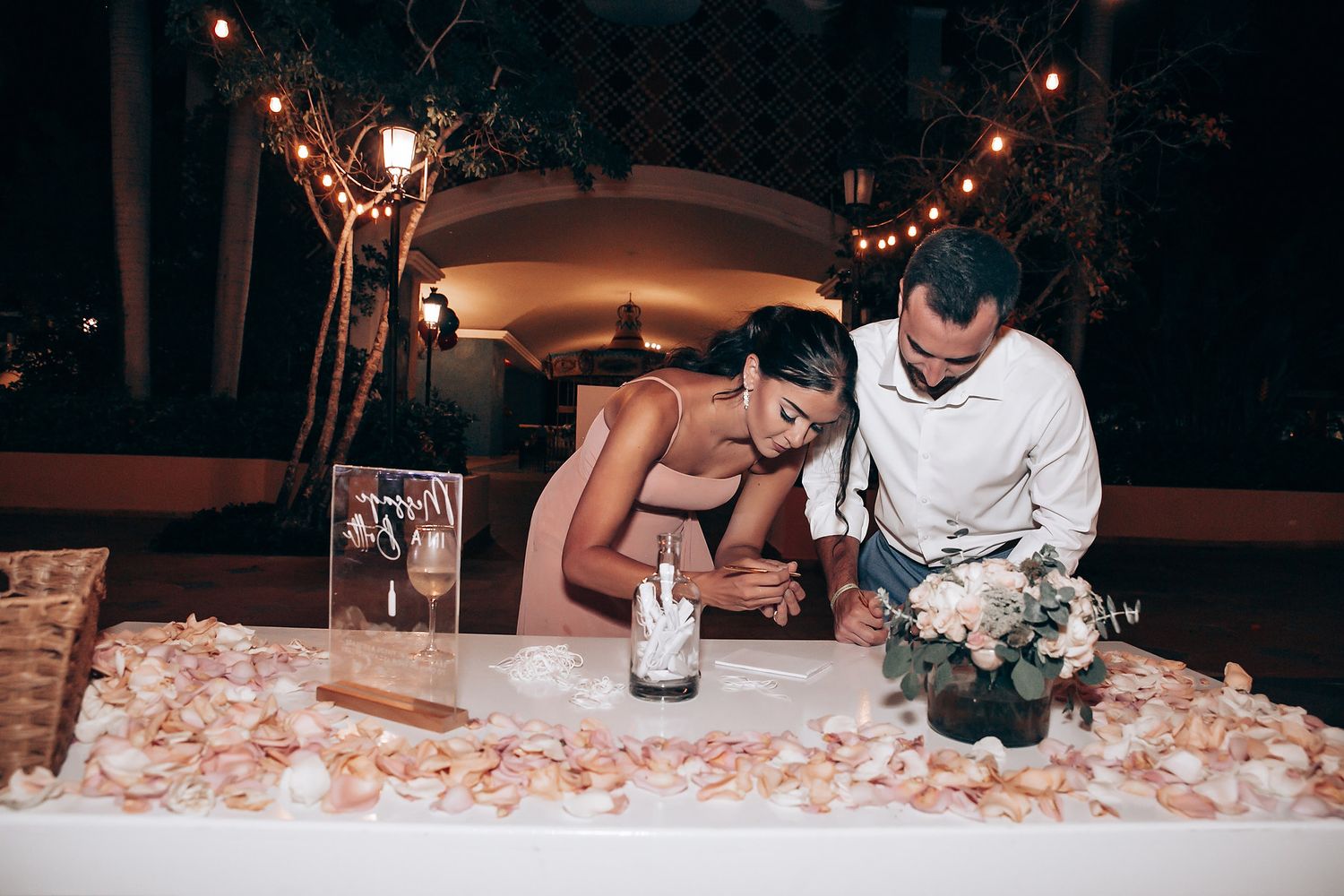 Romantic evening reception scene with soft lighting and floral centerpieces on decorated tables.