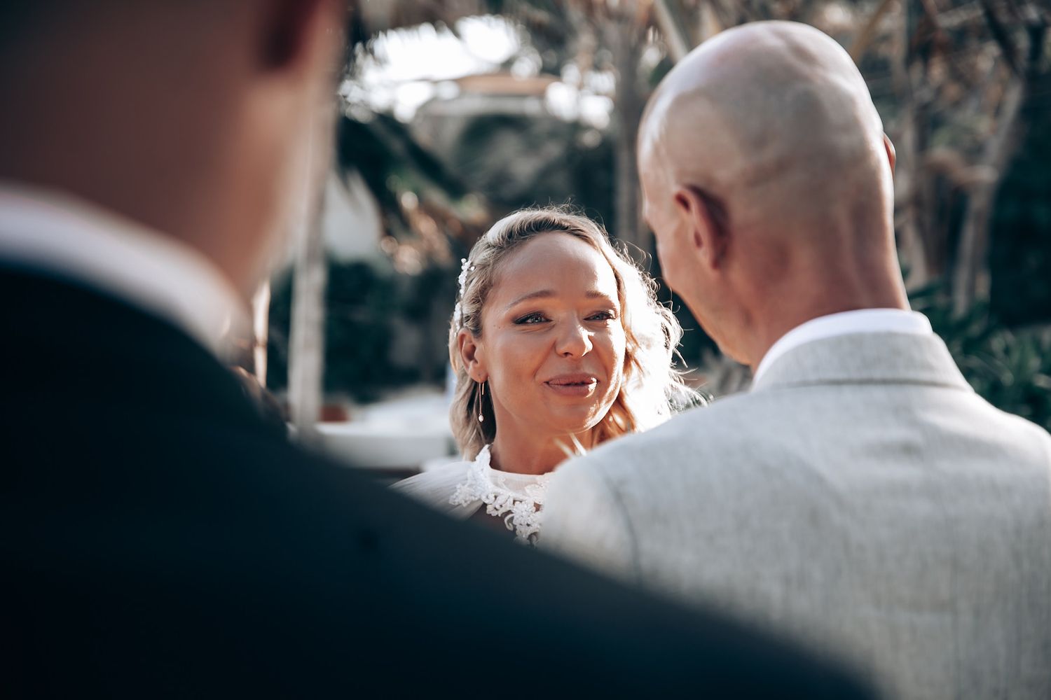 Wedding ceremony captured from behind officiant during outdoor service.