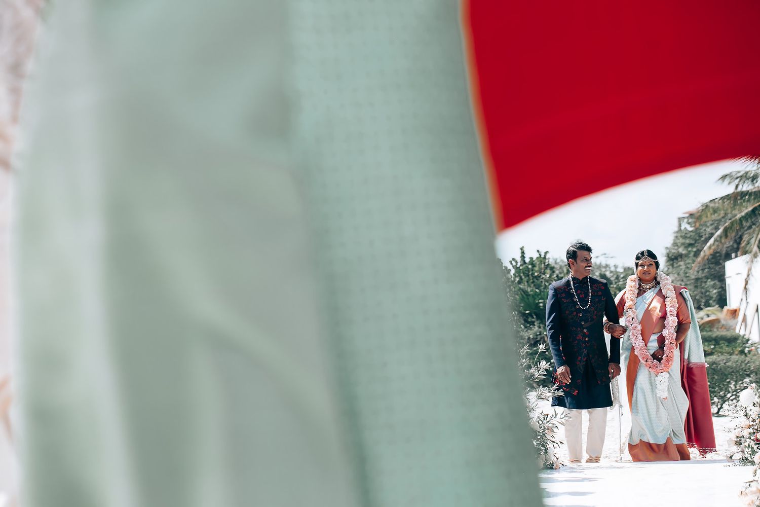 Outdoor beach wedding ceremony setup with red and mint green color scheme.