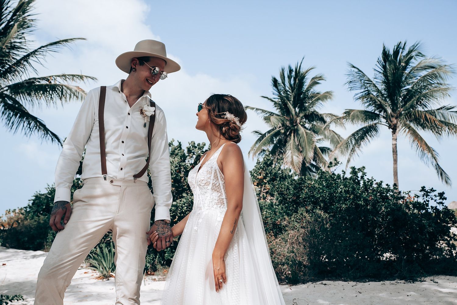 A tropical beach wedding scene with palm trees swaying in the background.