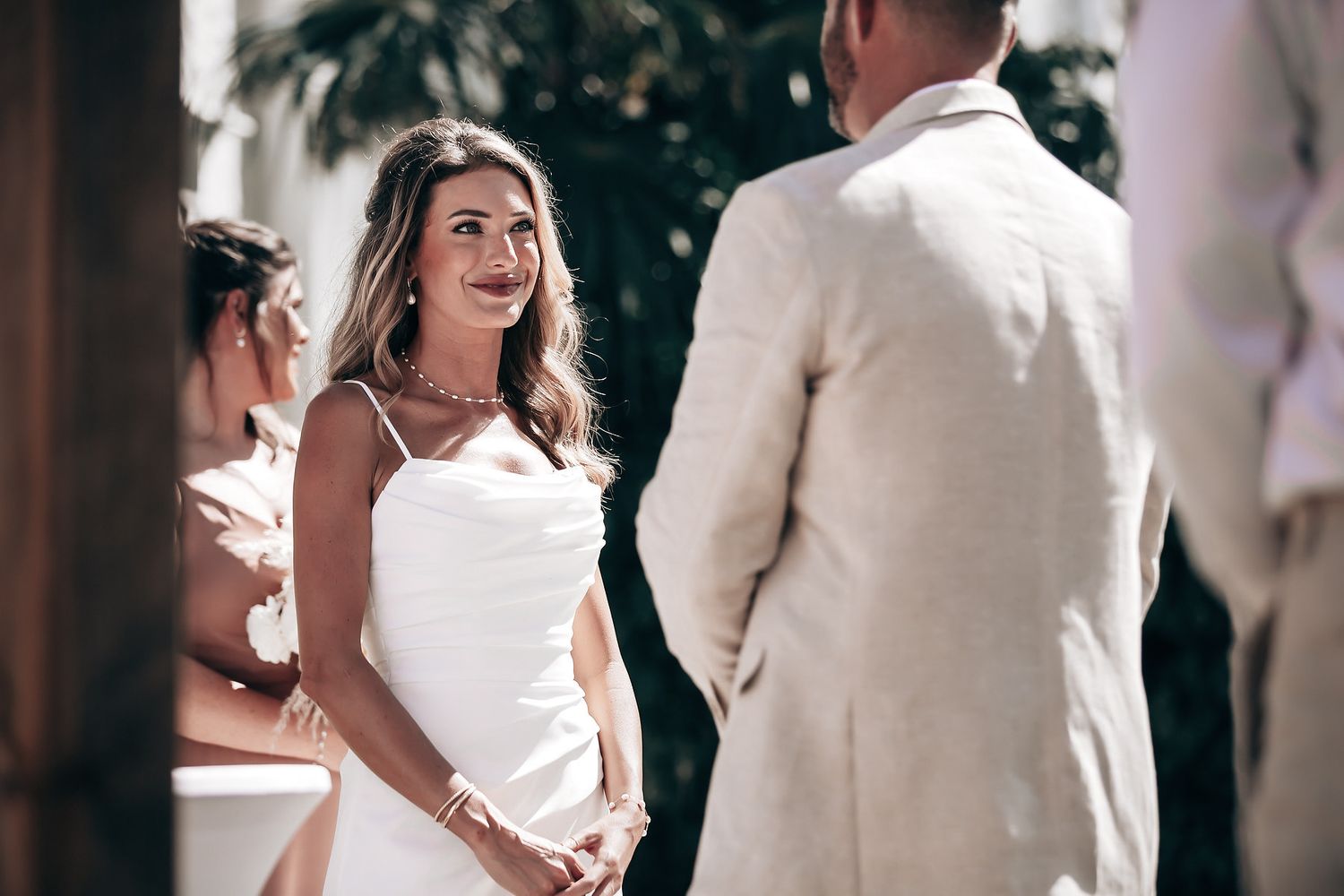 Two women in white wedding dresses stand together and smile.