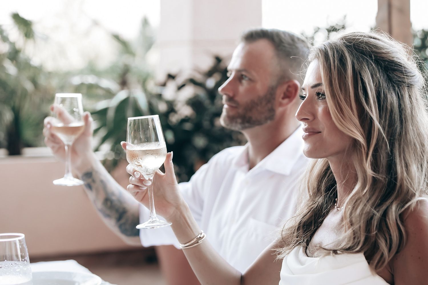 A couple toasting with champagne flutes at what appears to be a wedding reception.