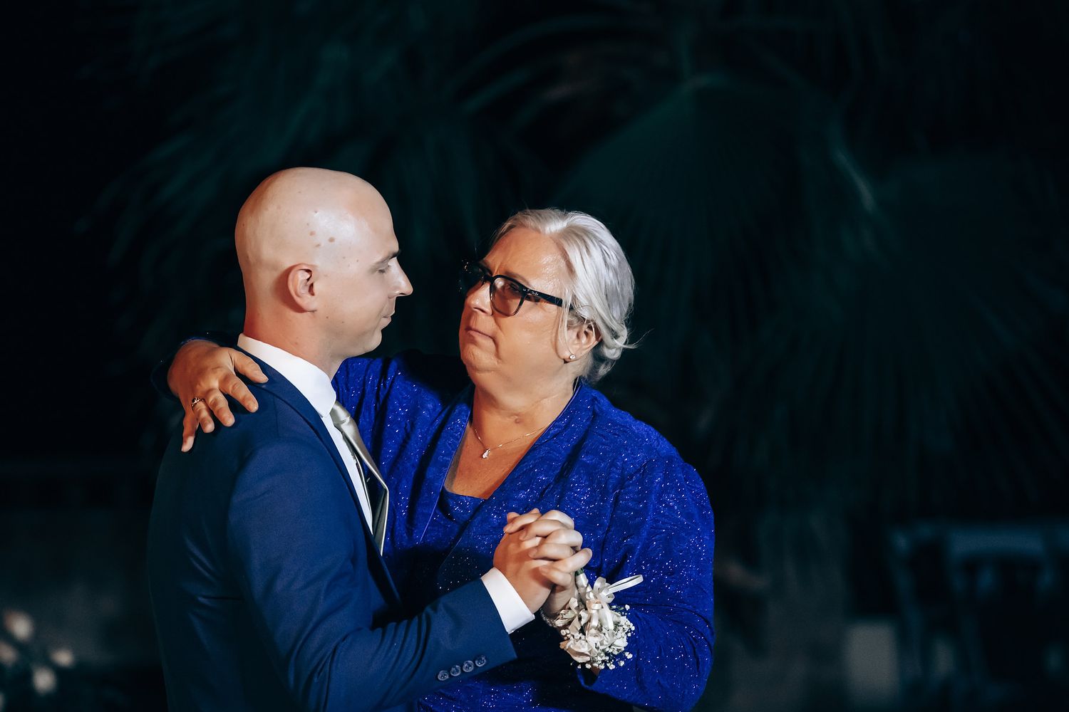 An elderly couple dancing together at a formal event, the woman wearing a blue dress.
