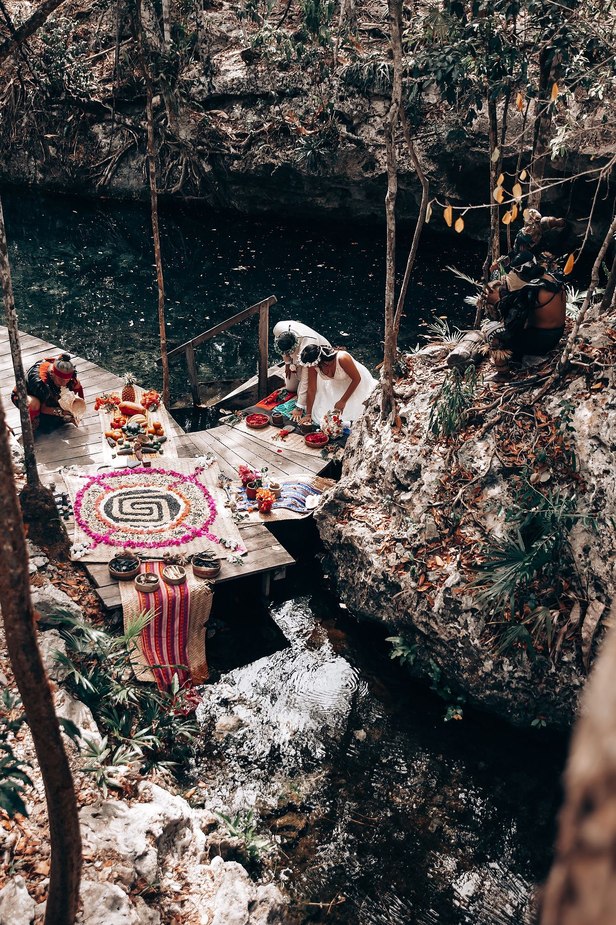 Decorative pink and white umbrellas arranged in a natural cave or grotto setting for a wedding ceremony.