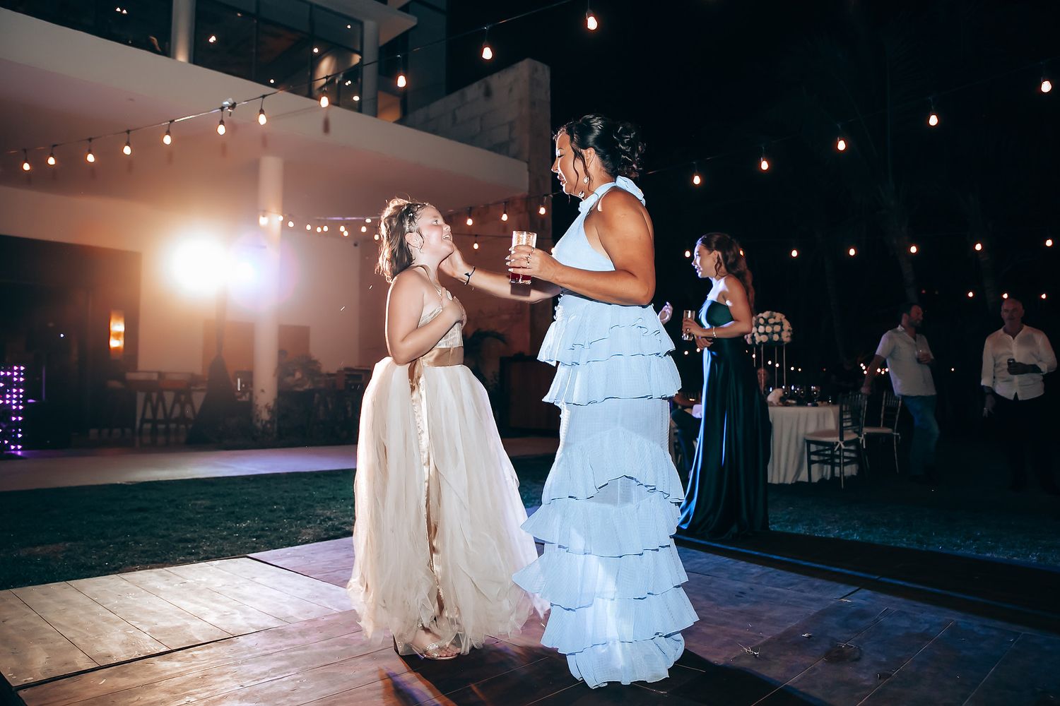 Wedding dance floor moments captured under romantic string light illumination.