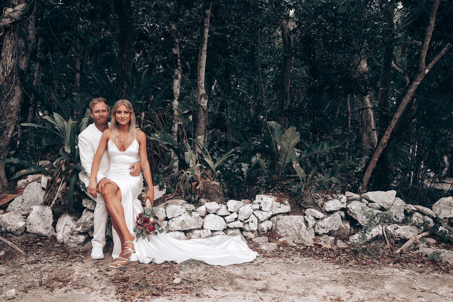 A wedding celebration captured in a rustic woodland setting with stone walls and natural forest backdrop.