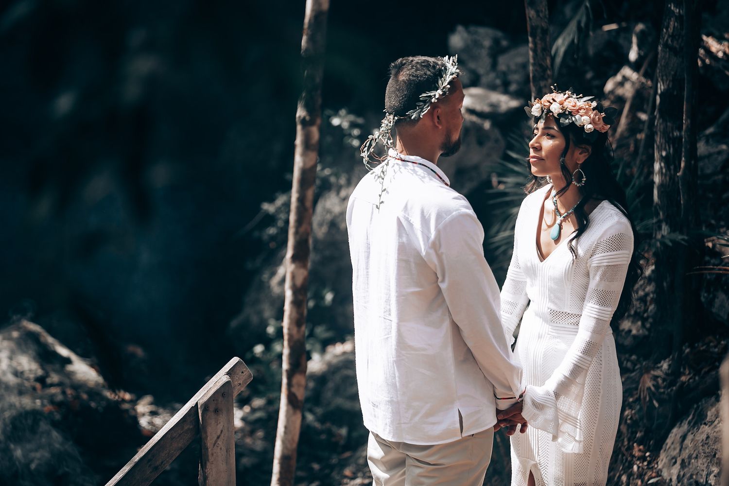 People in white clothing participate in a spiritual gathering in a natural forest setting.