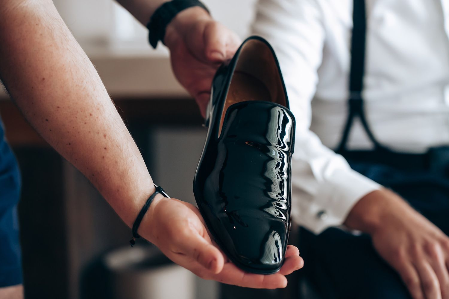 A close-up shot of someone holding a polished black leather dress shoe.