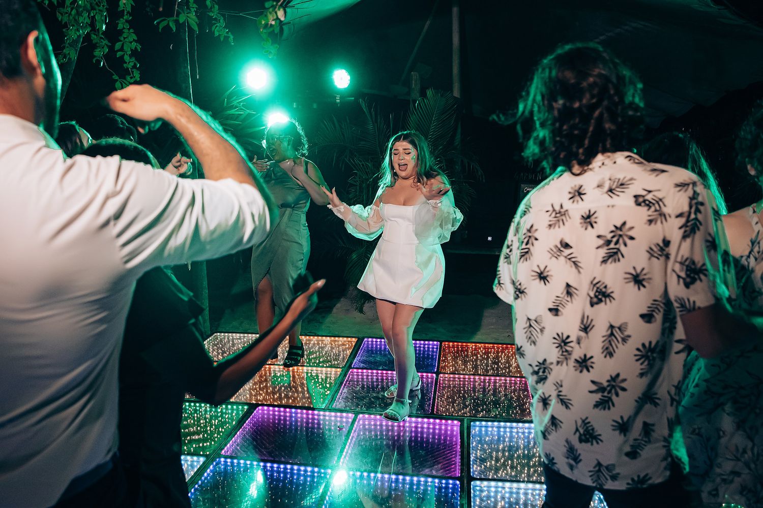 Colorful LED dance floor glowing with green and purple lights as guests dance at an outdoor celebration.