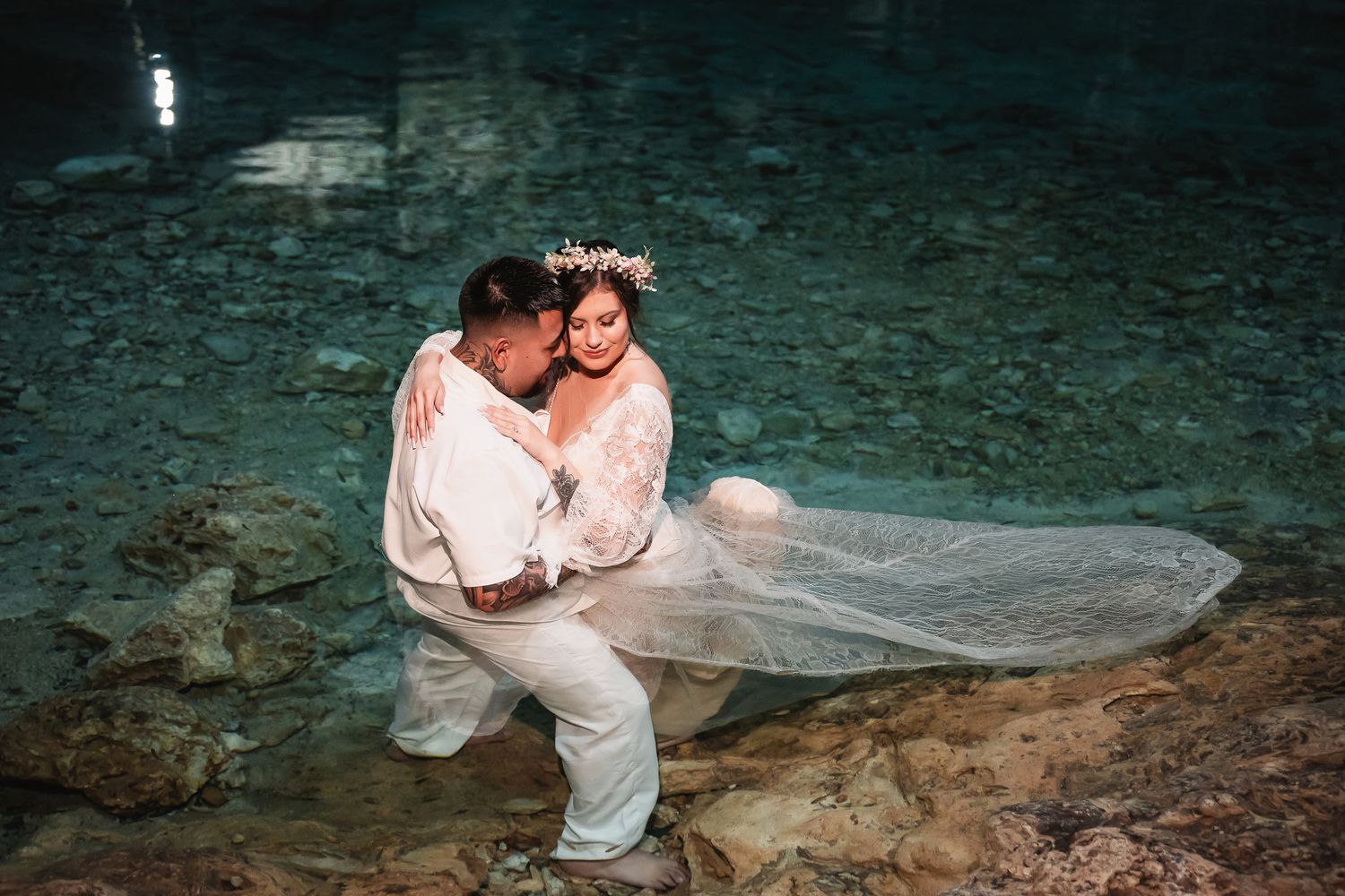 Intimate moment captured between newlyweds in the ethereal waters of a sacred cenote cave.