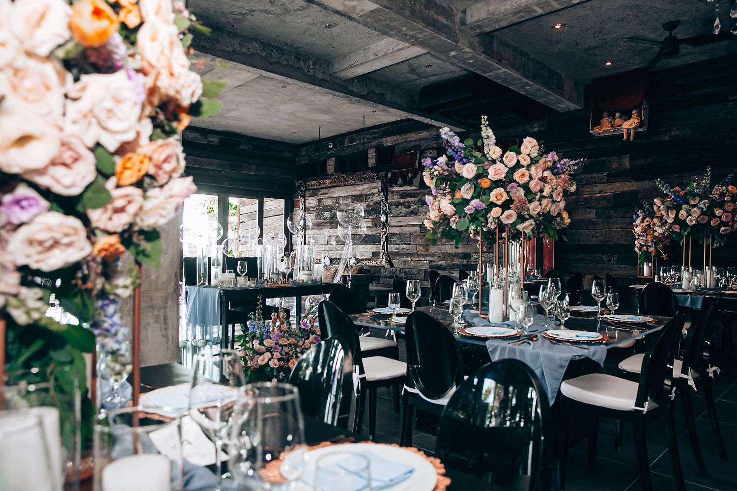 Elegant wedding reception venue with floral centerpieces and crystal chandeliers in a dark, moody atmosphere.