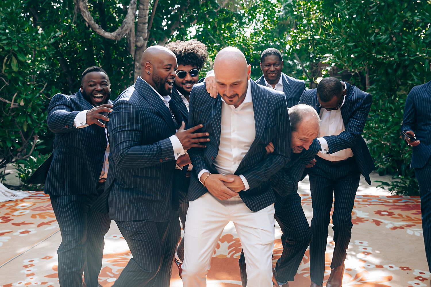 Wedding party celebrating and laughing together outdoors in a garden setting.