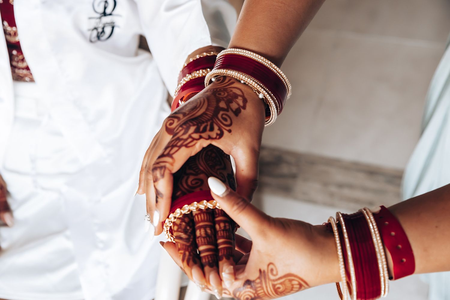 Detailed view of traditional henna designs on hands with red and gold bangles.