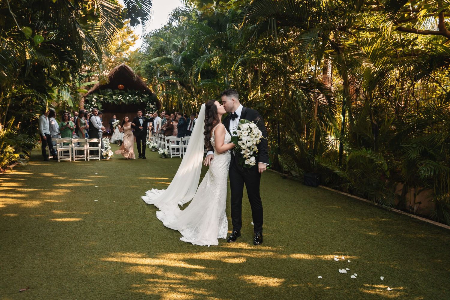 Sunset wedding ceremony in a lush garden setting with golden light filtering through the trees.