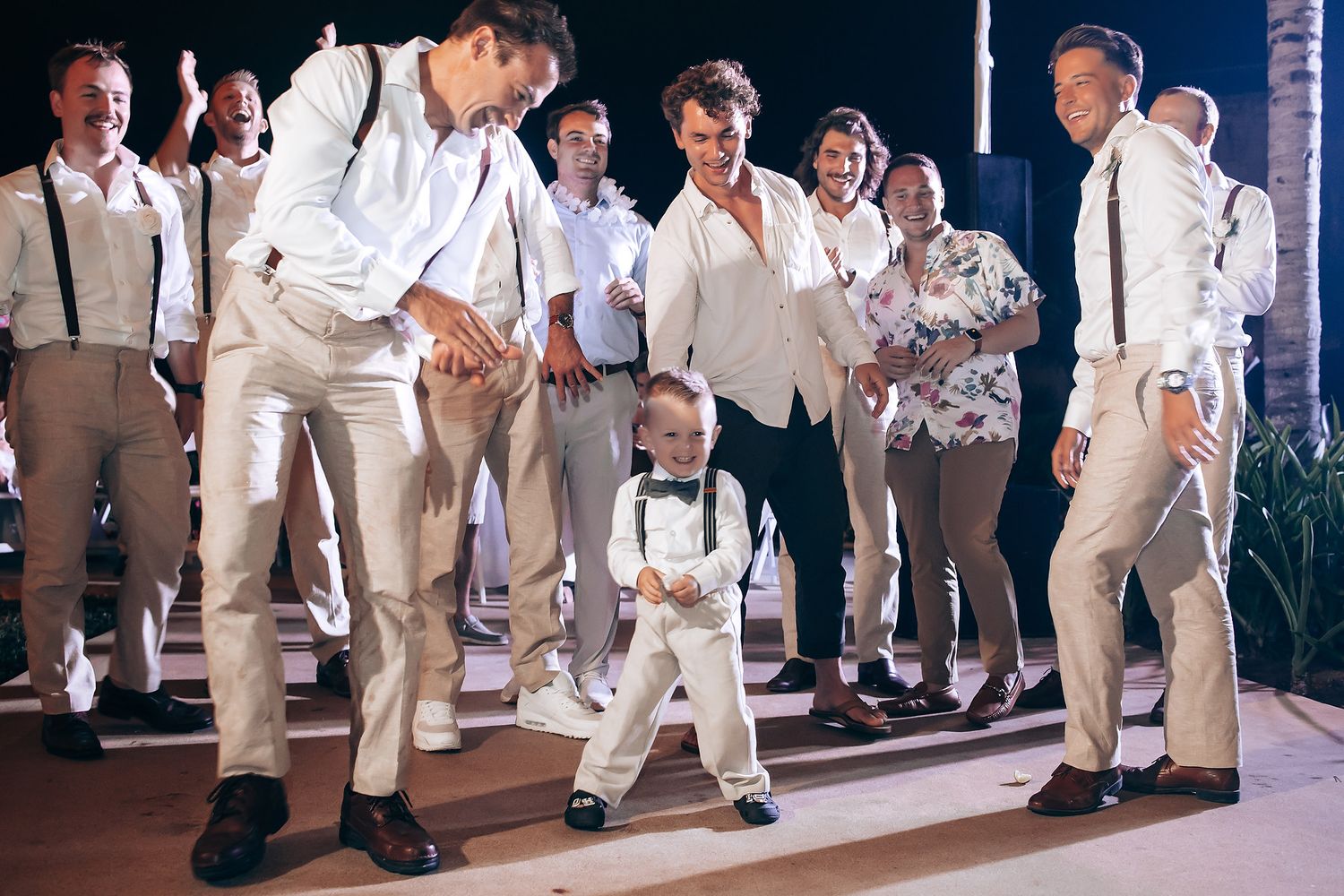 Wedding guests dancing in formal attire during an evening reception.