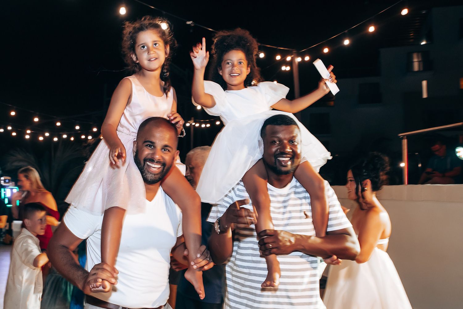 People in white and striped outfits dancing and celebrating at a summer party.