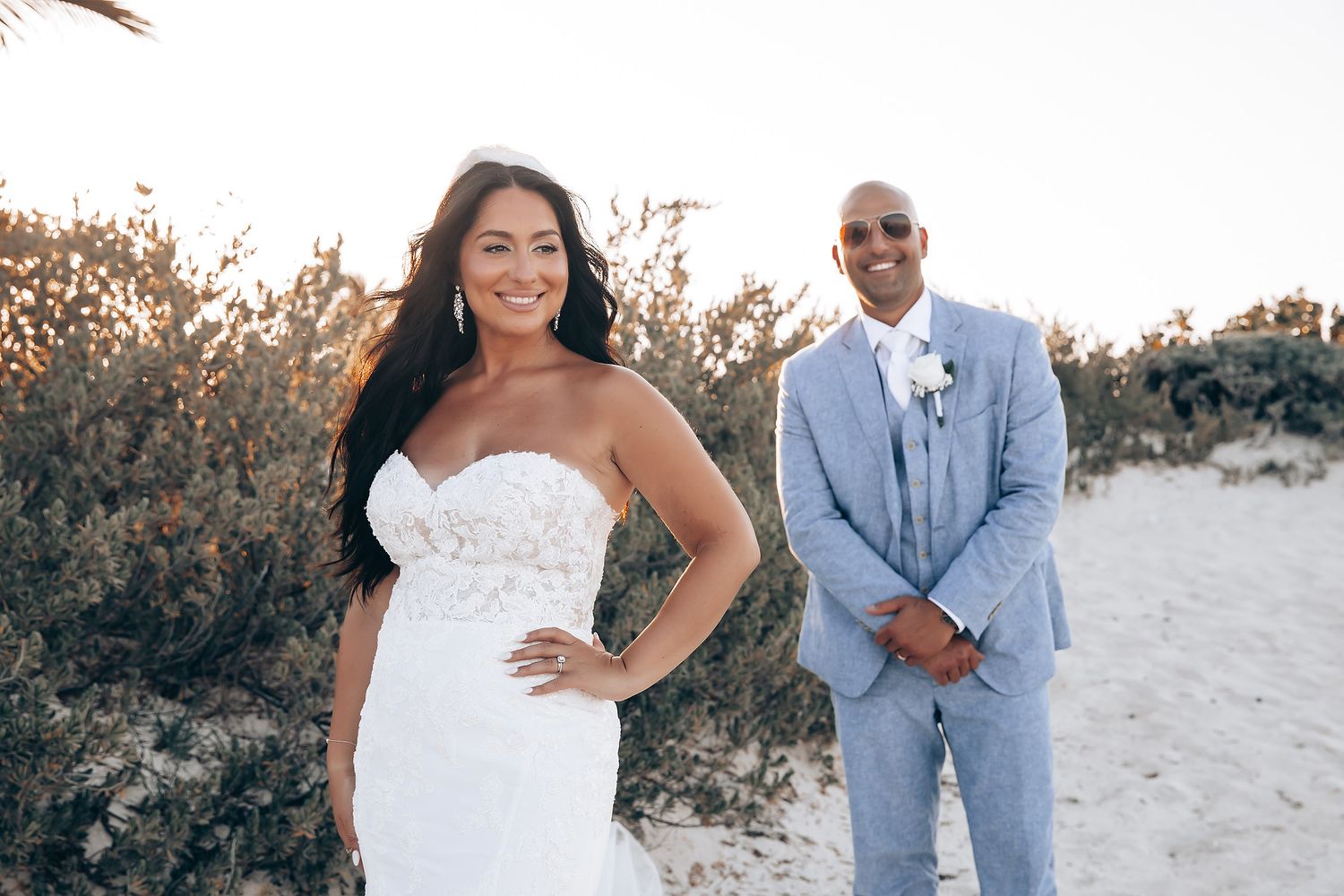 Romantic beach wedding photoshoot with couple in formal attire against natural coastal backdrop.