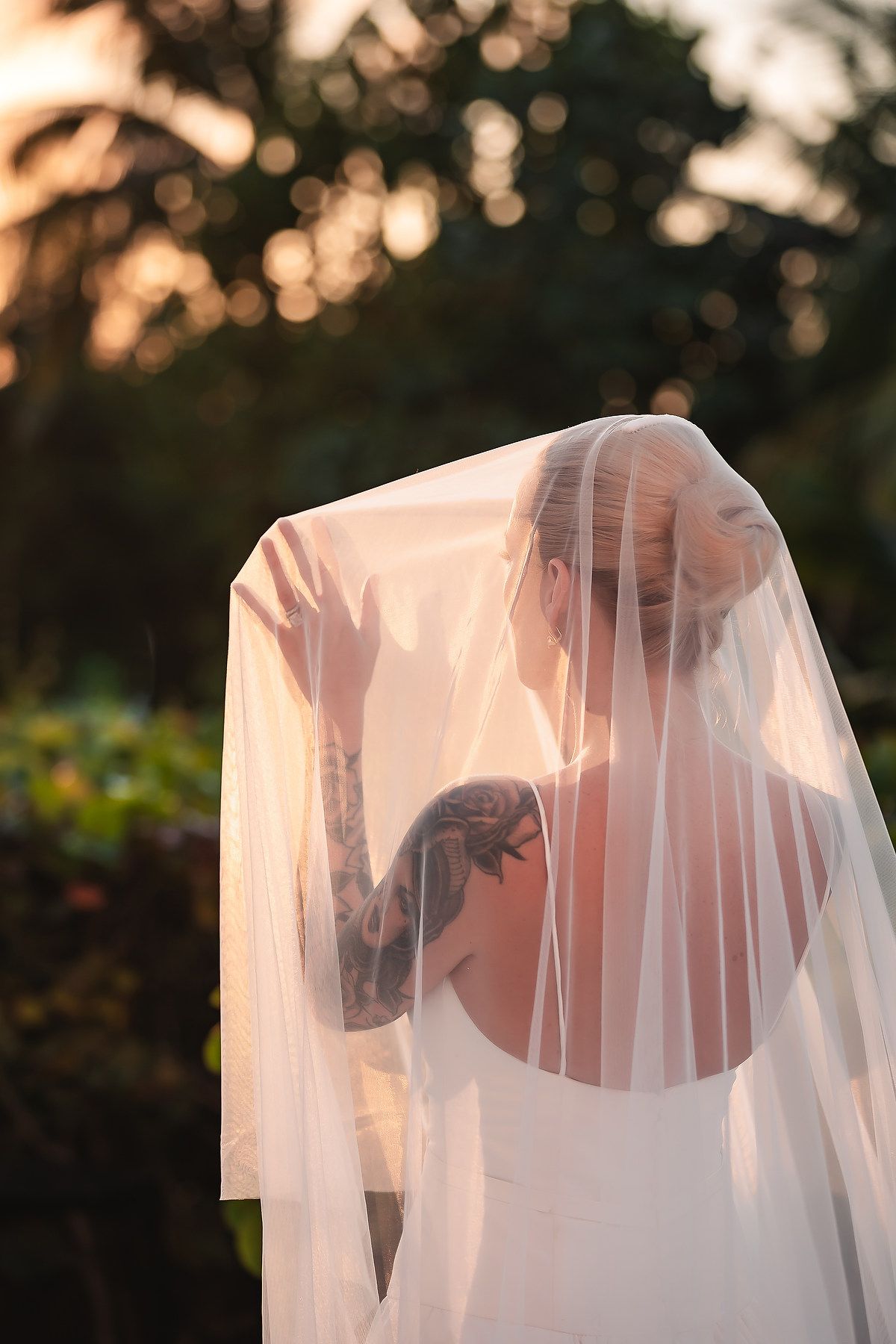 Romantic sunset bridal portrait with sheer veil creating dreamy atmosphere.
