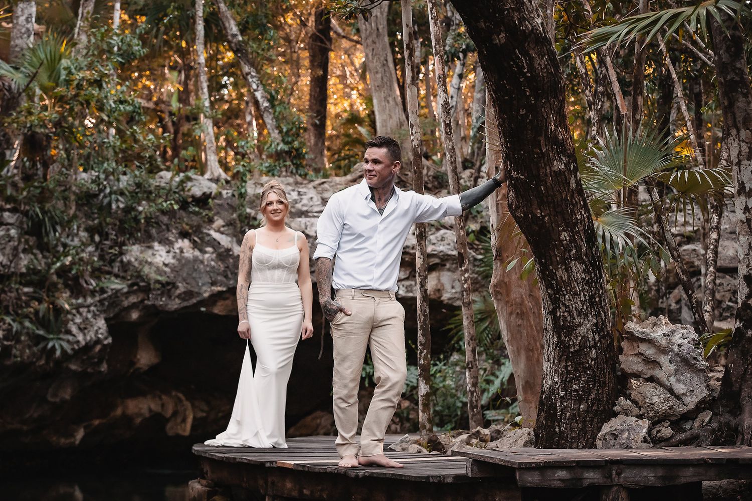 A romantic moment captured on a stone wall surrounded by tropical foliage.