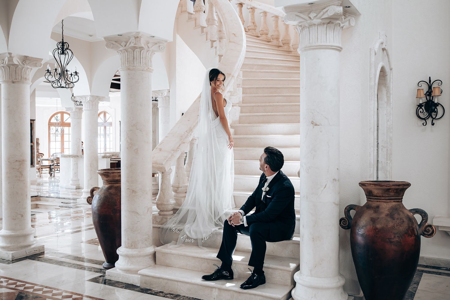 A series of elegant black and white photos showing people in formal attire posing in a grand white columned hallway.